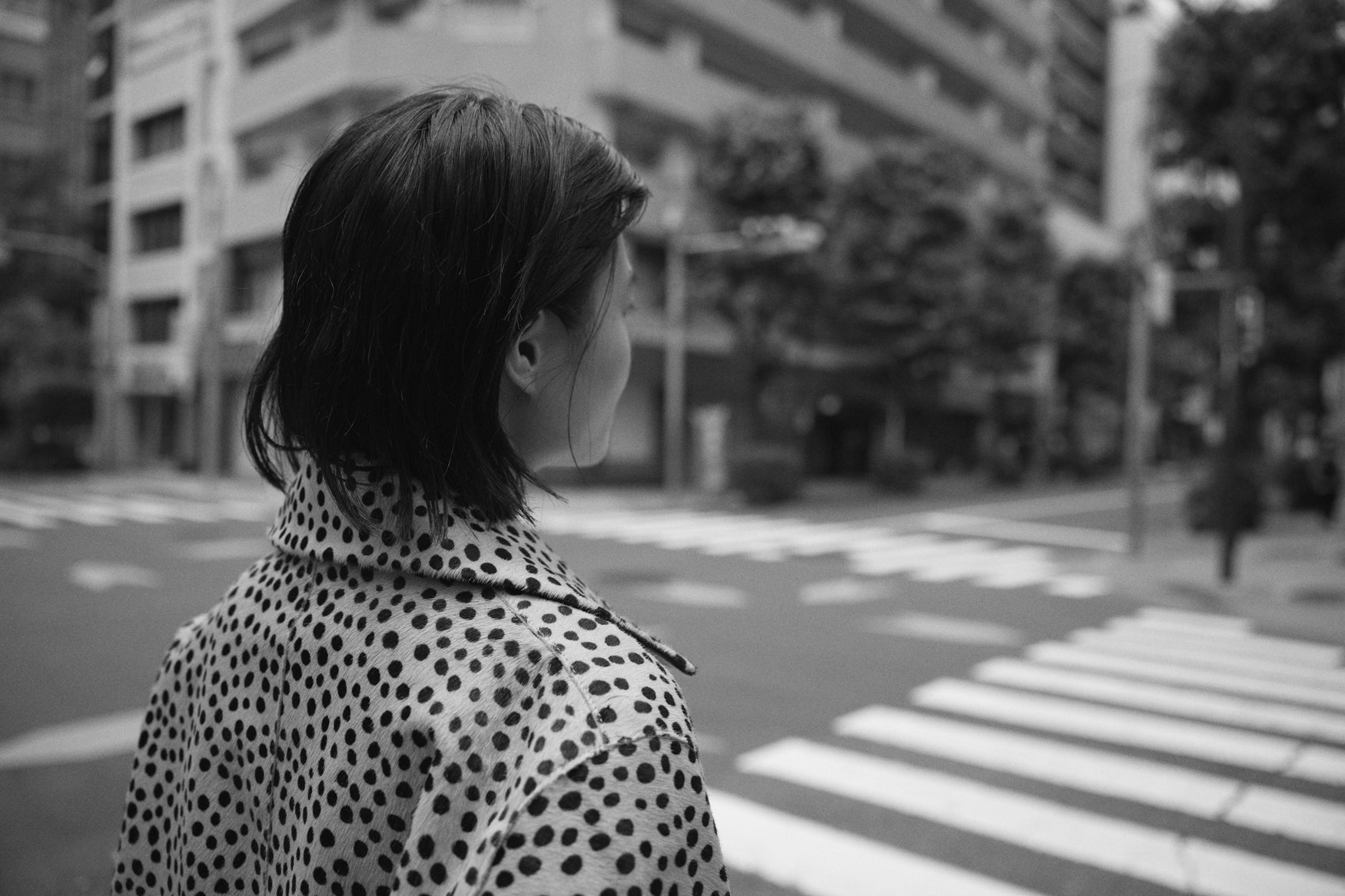Woman standing at a crossroad wearing a cheetah print coat 