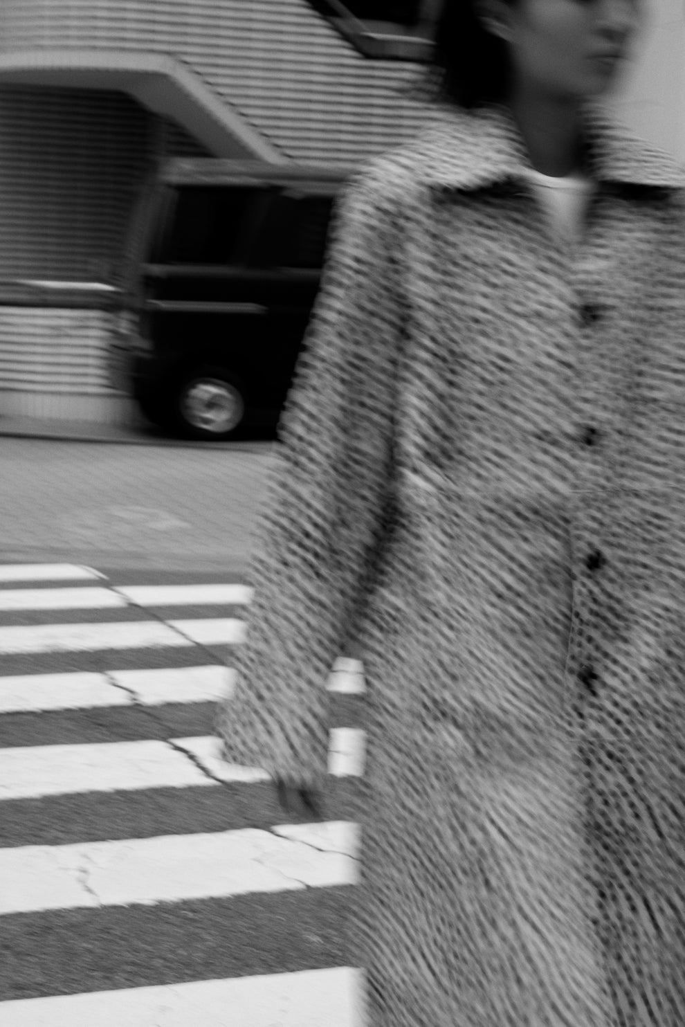 Blurry photo in movement of a woman walking on a crossroad wearing a cheetah print coat. 