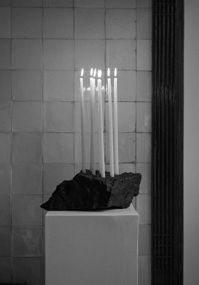 Sculptural Stone Candle Holder on a pedestal with seven lit taper candles, handcrafted from leftover lava stone by Dutch artist Louis Crombag.