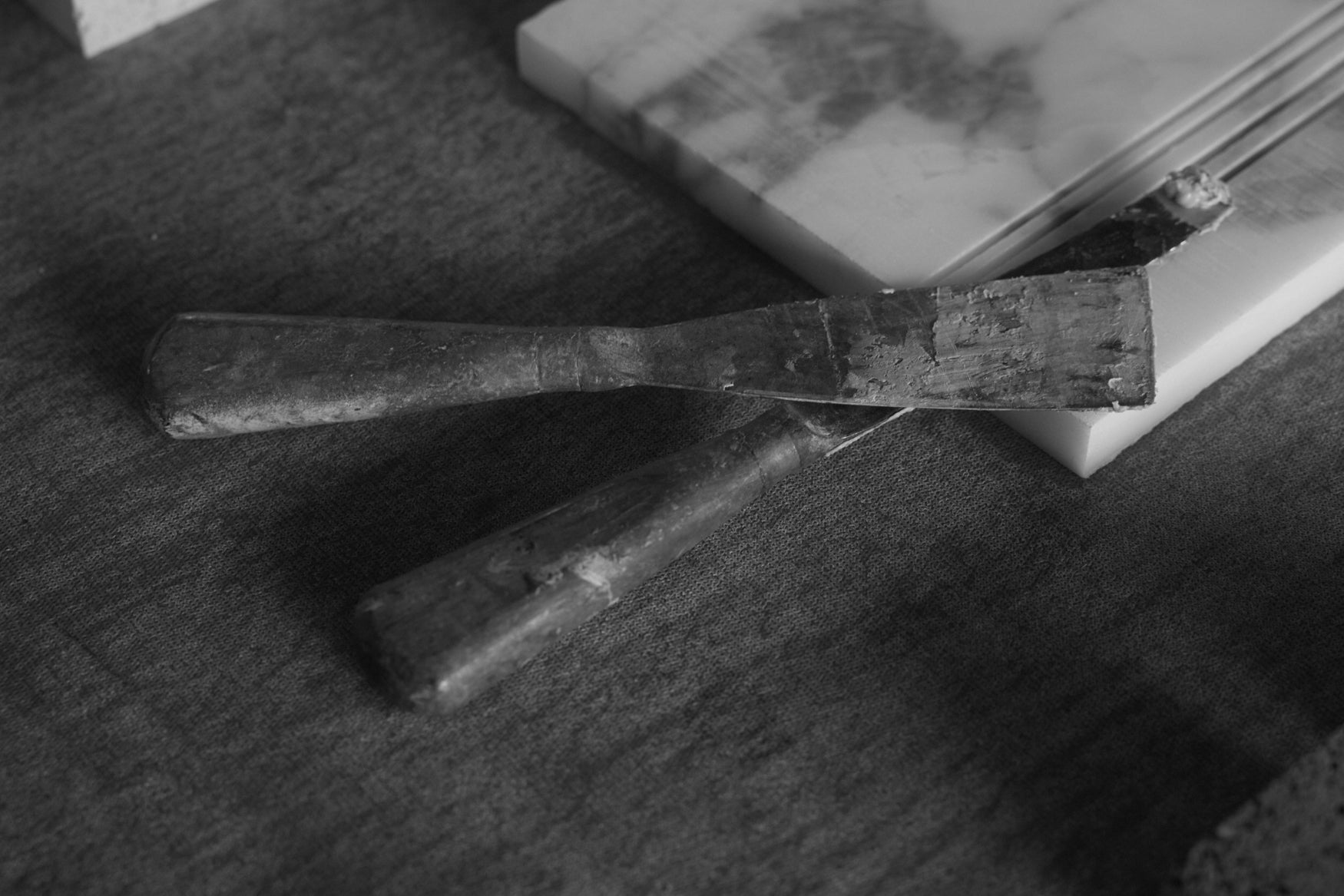 Two rustic looking spatulas stacked on a travertin plate 