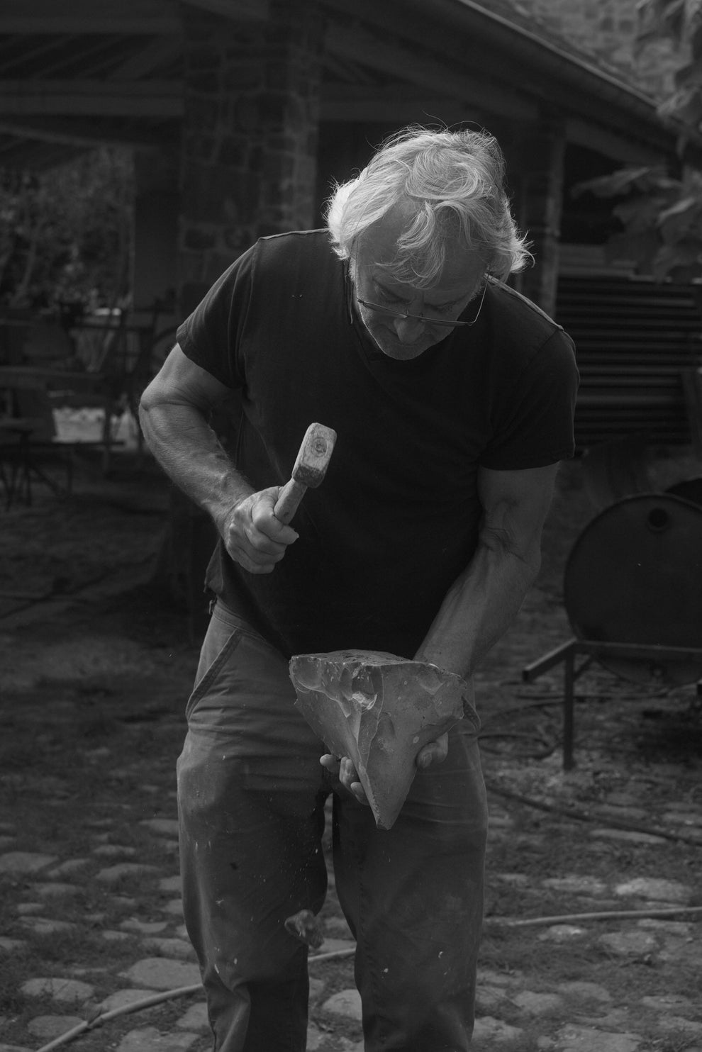 Man working on a piece of stone with a hammer 