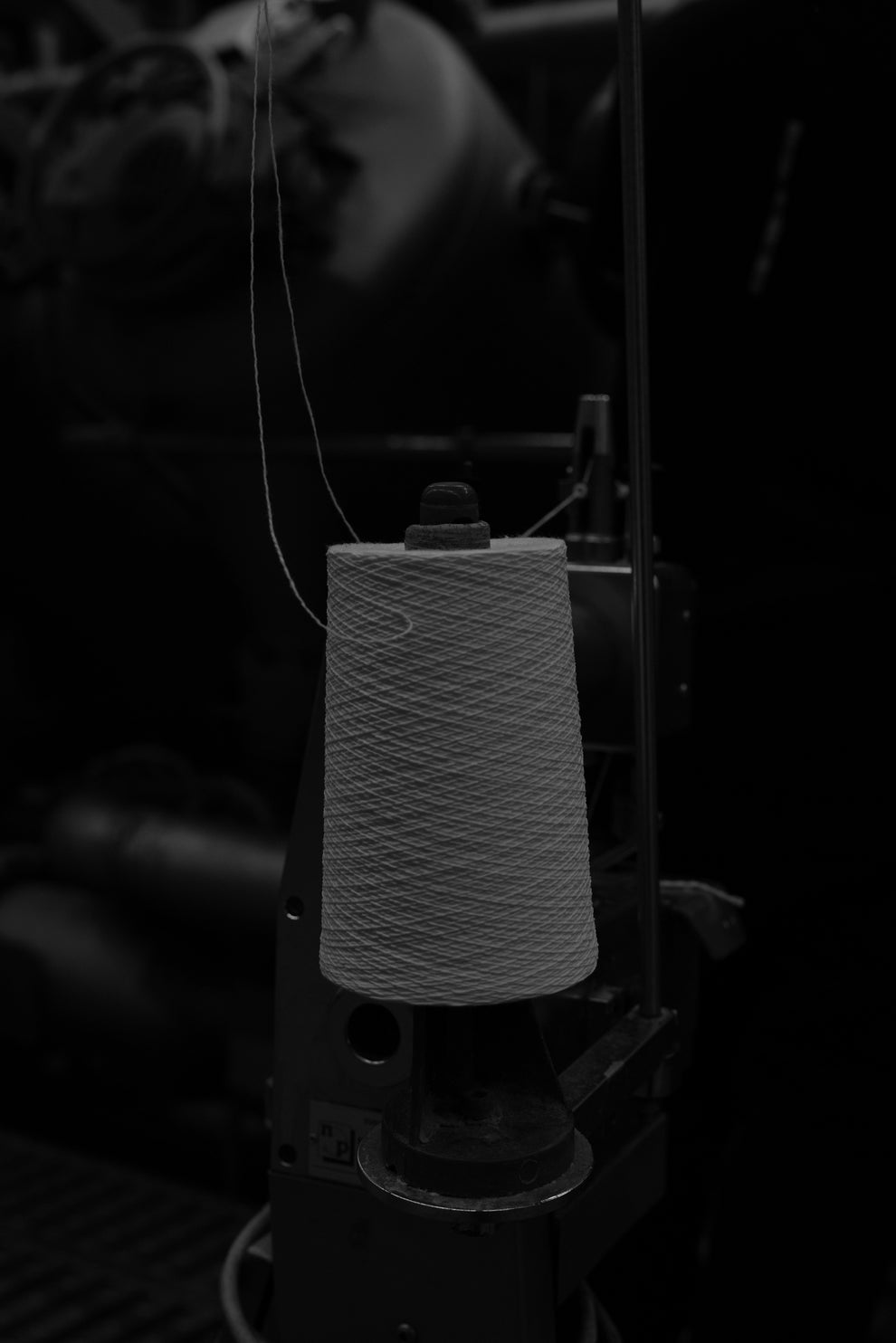 Close-up of a spool of thread on a sewing machine in black and white