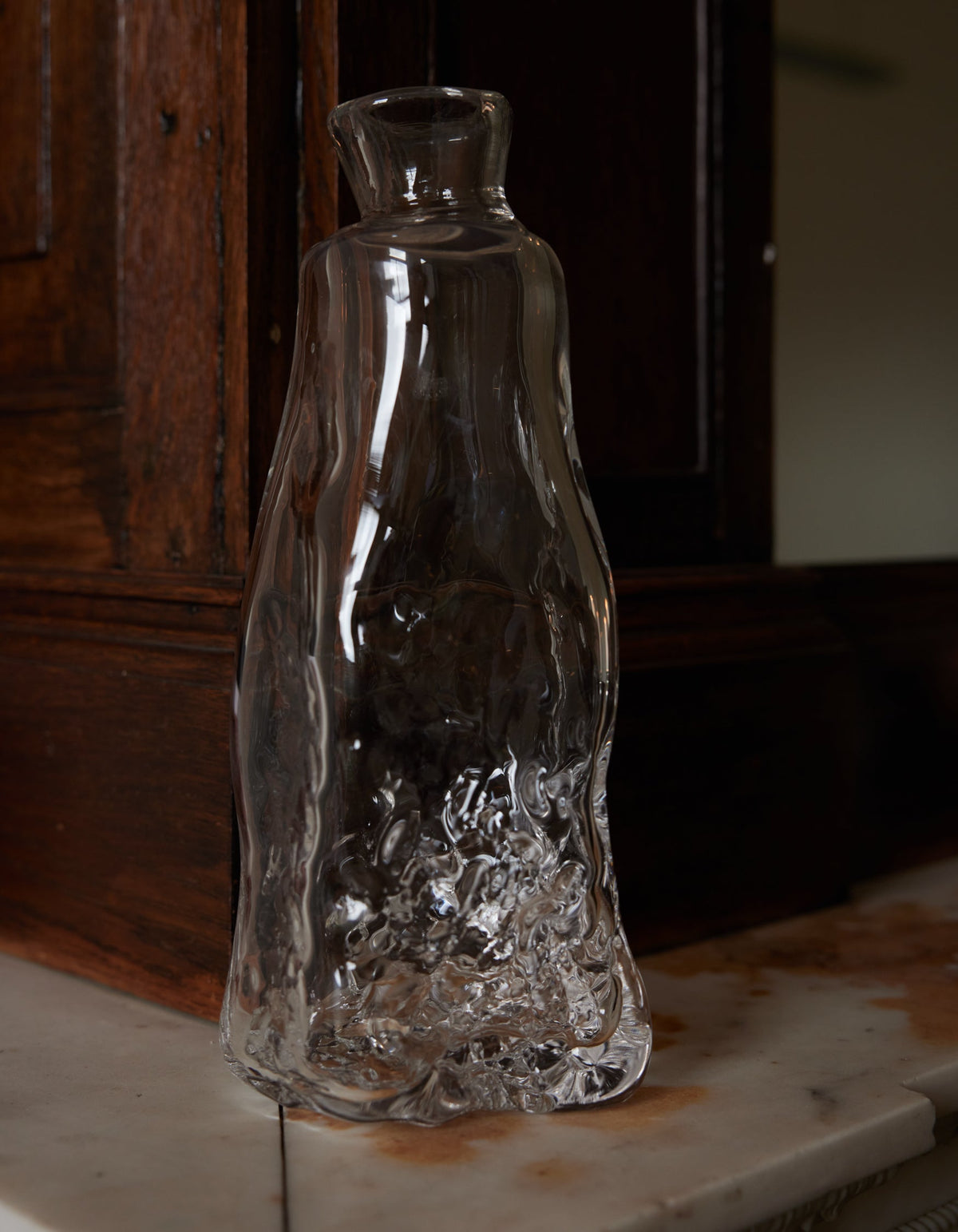 Blown vase | Glass: A clear, hand-blown glass vase with an organic, wavy silhouette and textured base, crafted by Szkło Studio, displayed on a stone ledge.