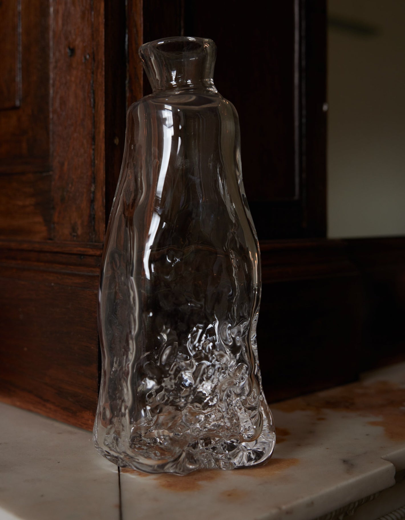 Blown vase | Glass: A clear, hand-blown glass vase with an organic, wavy silhouette and textured base, crafted by Szkło Studio, displayed on a stone ledge.