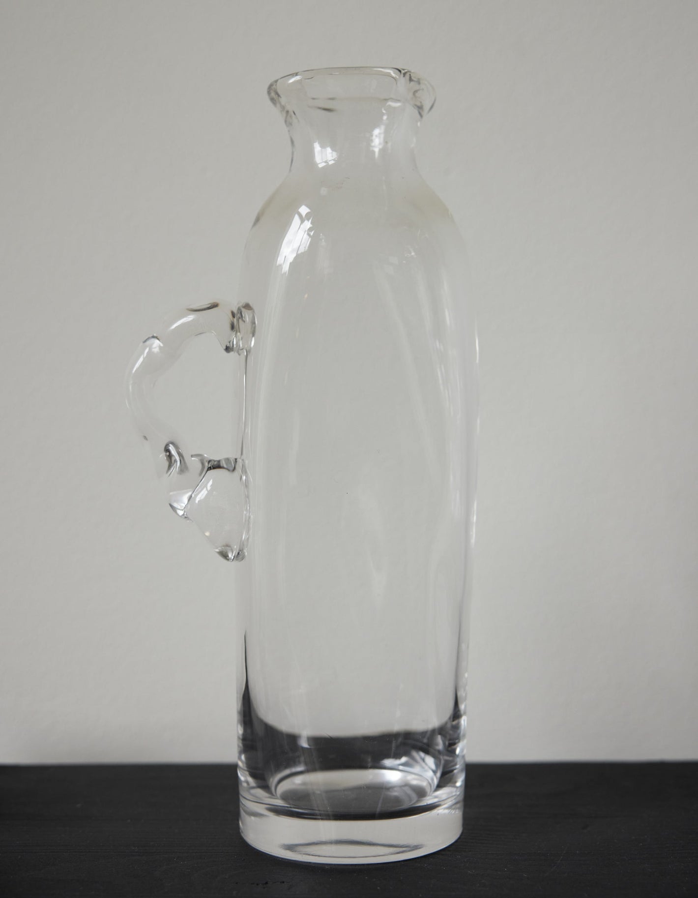 Large water carafe | Glass: A tall, hand-blown clear glass carafe with a stylized handle, showcasing unique craftsmanship by Szkło Studio.
