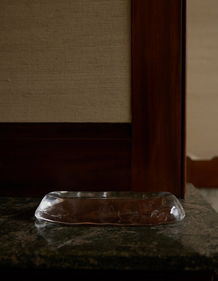Close-up of Long trinket | Glass, an elegant clear glass pen rest, featuring a black pen with gold trim on a wooden desk.