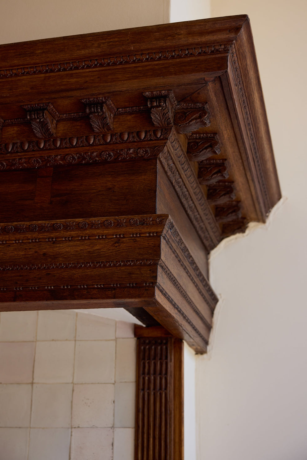 Carved wooden cornice on a wall covered in tiles 