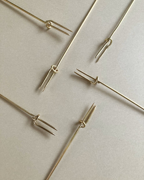 Vine Fork: Handcrafted, gold-tone, two-pronged picks inspired by nature, designed by Misae Nikkei in Kyoto, ideal for skewering appetizers like olives or cheese.