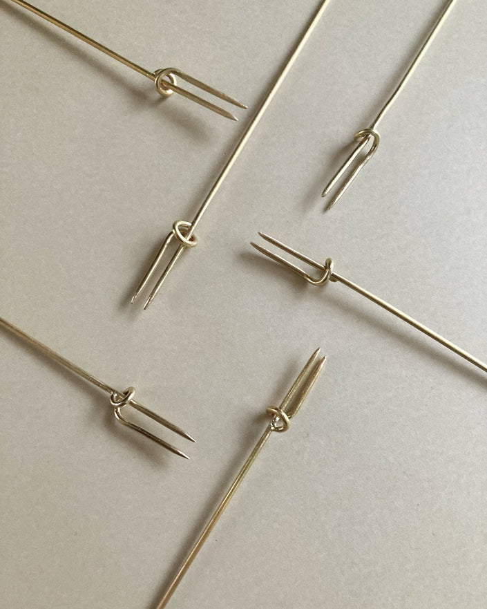 Vine Fork: Handcrafted, gold-tone, two-pronged picks inspired by nature, designed by Misae Nikkei in Kyoto, ideal for skewering appetizers like olives or cheese.