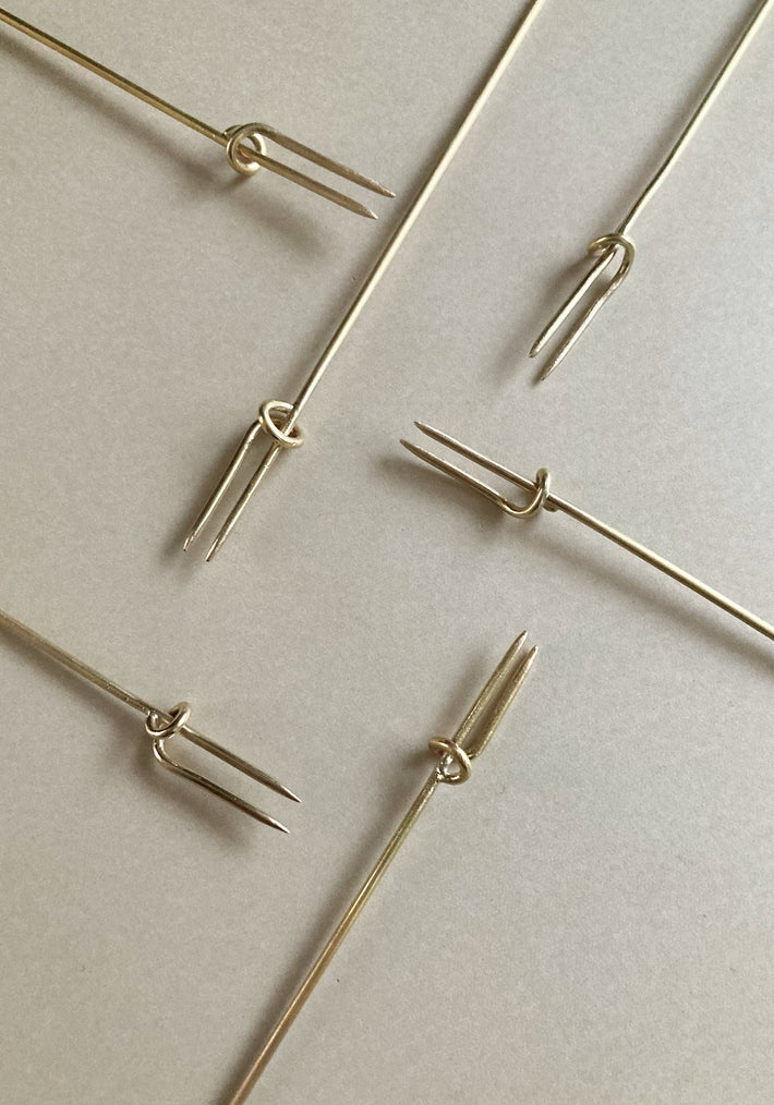 Vine Fork: Handcrafted, gold-tone, two-pronged picks inspired by nature, designed by Misae Nikkei in Kyoto, ideal for skewering appetizers like olives or cheese.