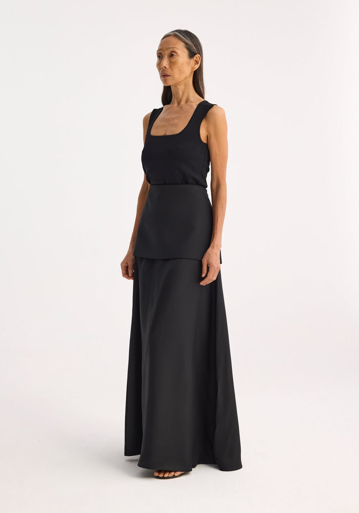 Bustier shaped knitted top in black, featuring a fitted, sleeveless design with a scoop-neck, worn by a model with long straight hair, arms relaxed.