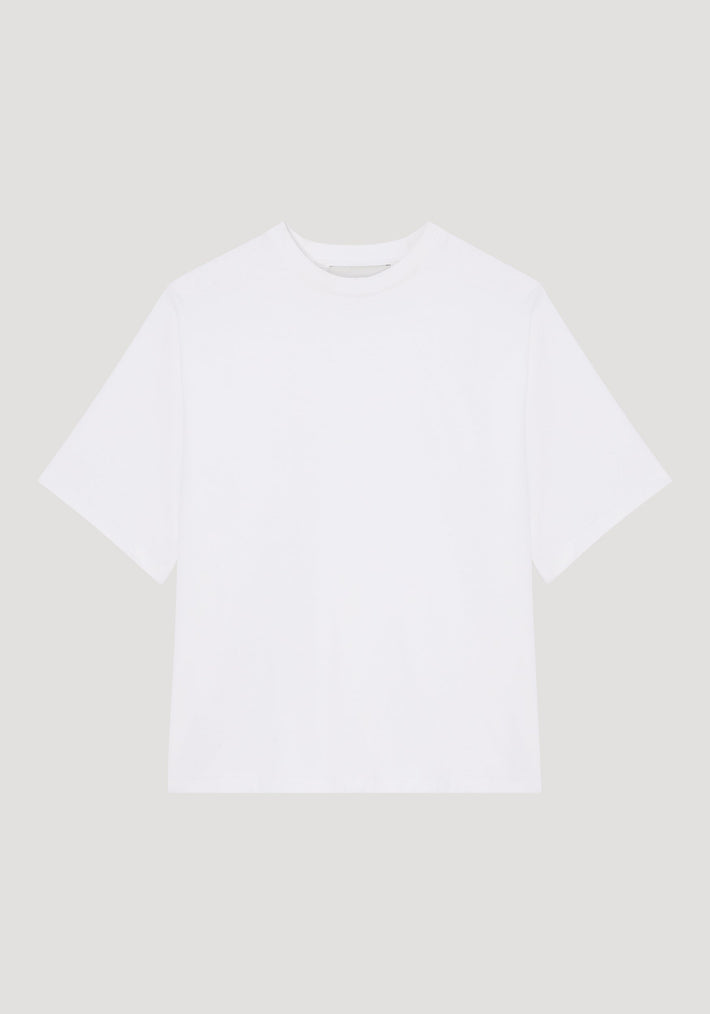 Oversized cotton t-shirt in optic white, featuring a relaxed fit with drop shoulders and crew neck, displayed flat with a small logo label on the sleeve.