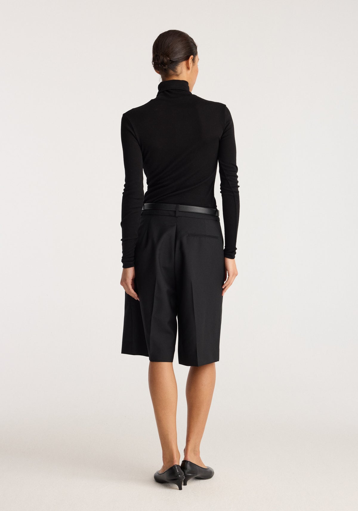 Fine merino turtleneck | black shown from the back on a model, featuring a fitted silhouette, long sleeves, and a high neck.