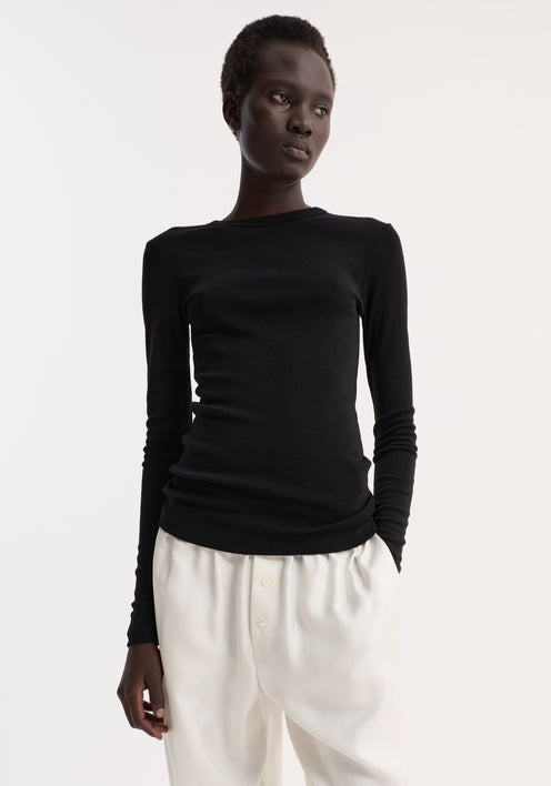 Model wearing Fine merino long sleeve in fitted silhouette, paired with high-waisted trousers and sandals, highlighting minimalist style.