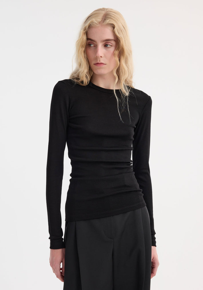 Model wearing the Fine merino long sleeve in black, a fitted 100% wool top, with wide-leg trousers, showcasing a classic and effortless style.