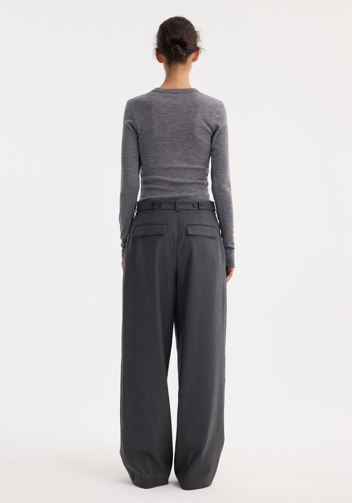 Back view of a person wearing a fitted Fine merino long sleeve in mid grey melange, tucked into high-waisted wide-leg trousers, hair styled in a bun.