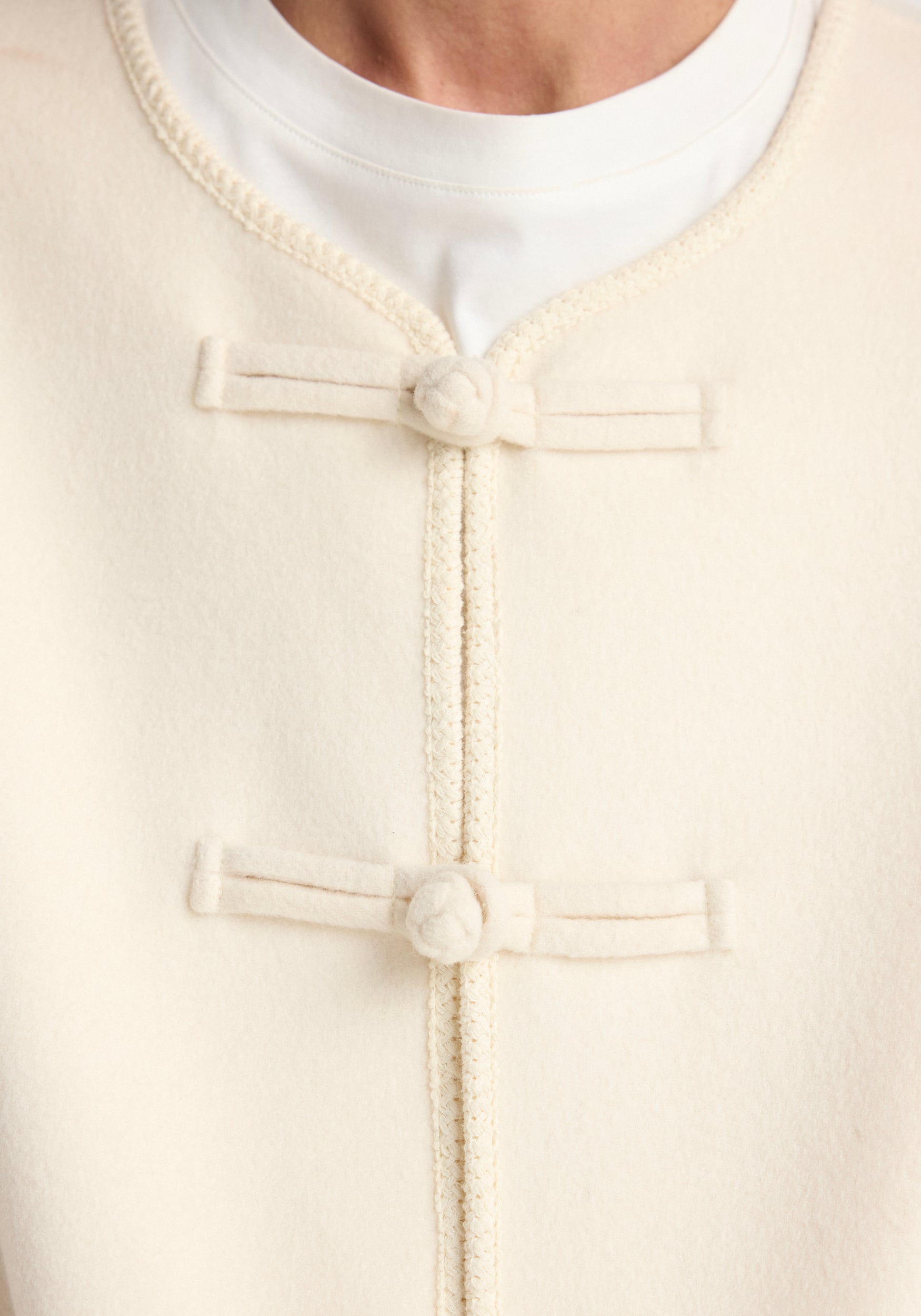 Close-up of the front closure details on the Double-faced wool pankou jacket | off white, showing the soft textured wool fabric and traditional knotted button fastenings.