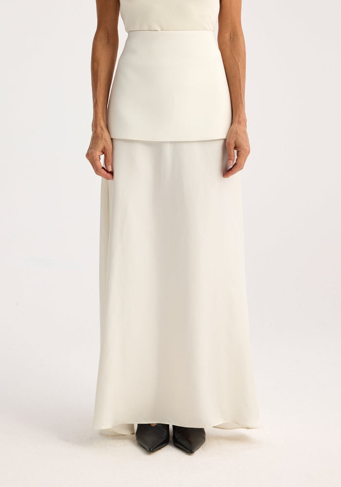 Model wearing Integrated fluid silk skirt | cream, showcasing a high waist and smooth silhouette with black pointed-toe shoes visible, emphasizing modern minimalism.