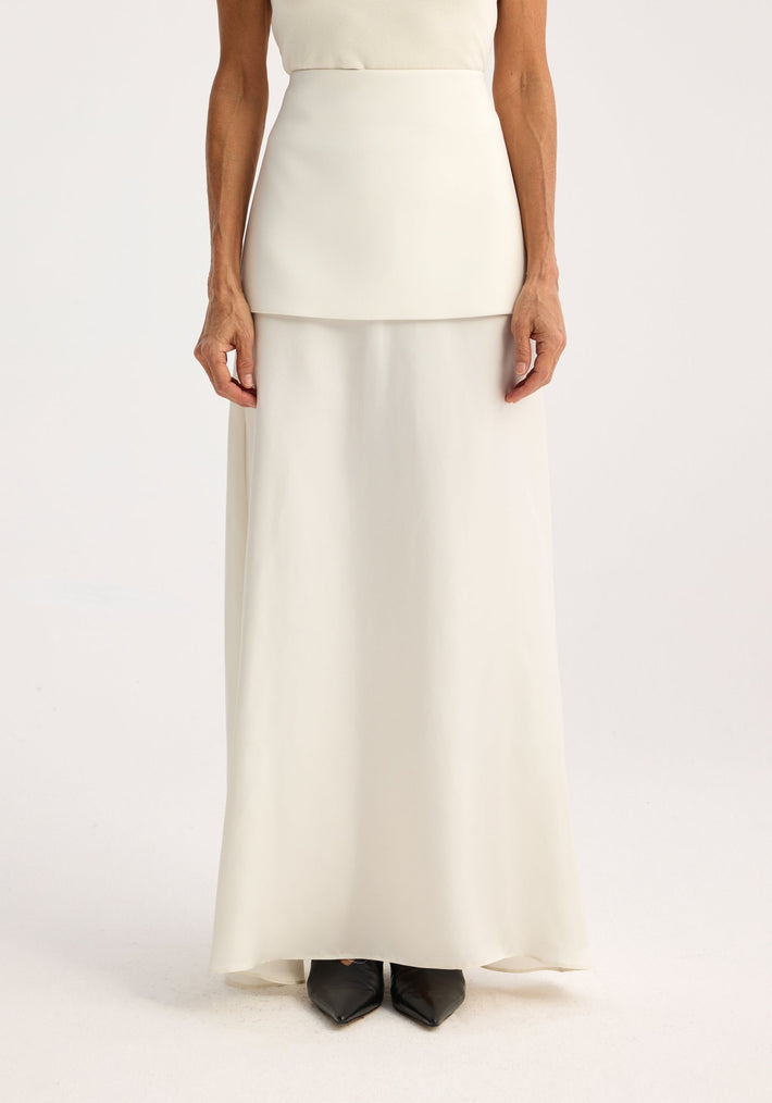 Model wearing Integrated fluid silk skirt | cream, showcasing a high waist and smooth silhouette with black pointed-toe shoes visible, emphasizing modern minimalism.