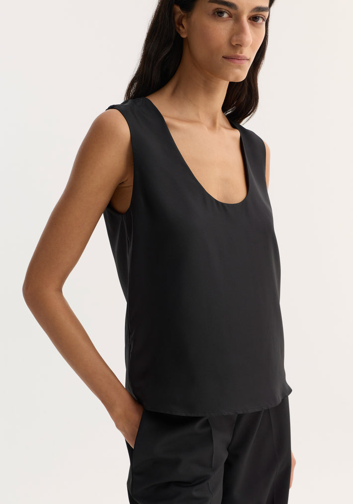 Scoop-neck silk top in black, featuring a wide scoop neckline and loose fit. Made from pure silk, ideal for minimalist layering. Model wears size EU 36.