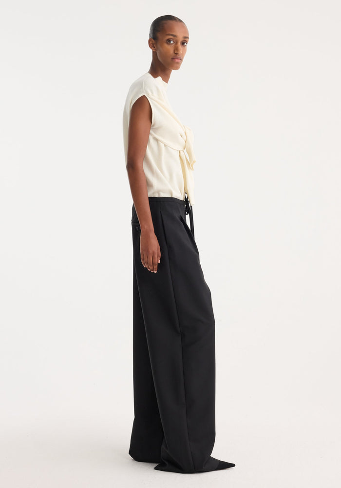 Model in profile wearing Relaxed drawstring trousers | black, featuring wide legs and a drawstring waist, paired with an ivory knit top.