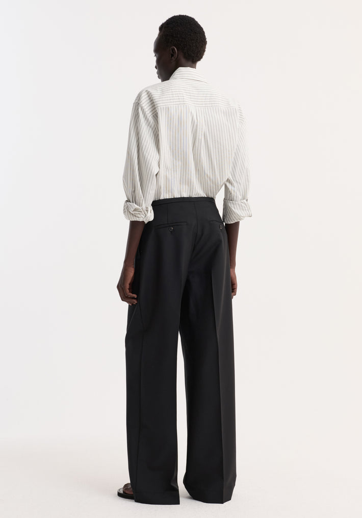 Model wearing Relaxed drawstring trousers in black, featuring wide-leg design, drawstring waistband, and front pleats, paired with an off-white pinstripe shirt.
