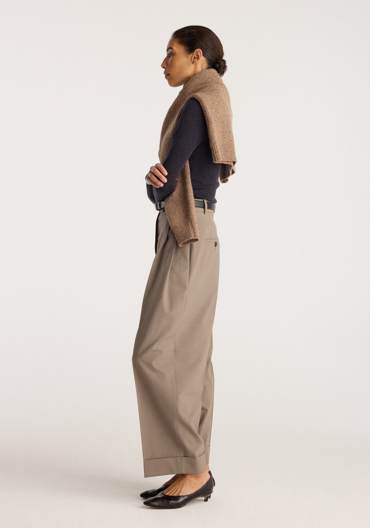 High-waist turn-up trousers | taupe shown in side profile on a model with a brown sweater draped over her shoulders and black flats