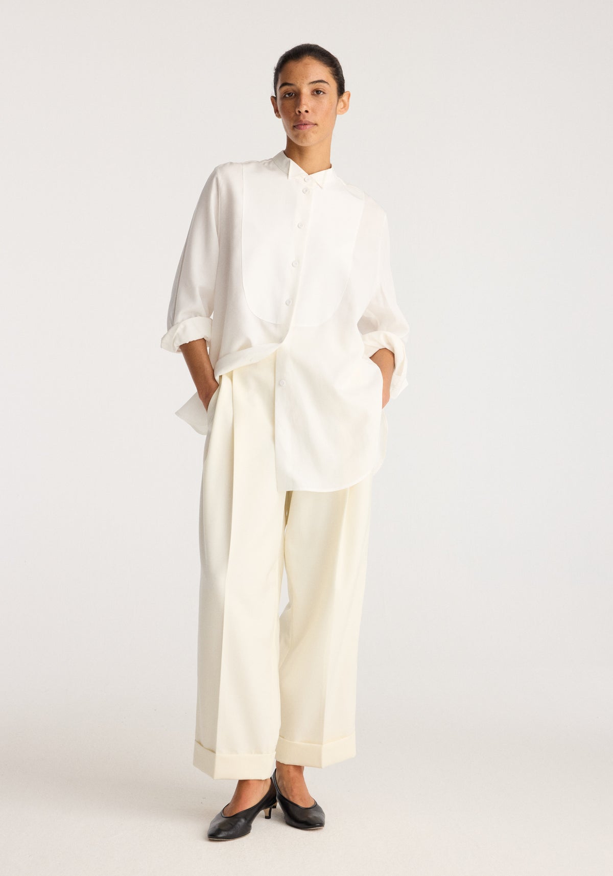 Tuxedo shirt | optic white worn by a model with rolled sleeves and a concealed button front styled with wide leg trousers and black loafers