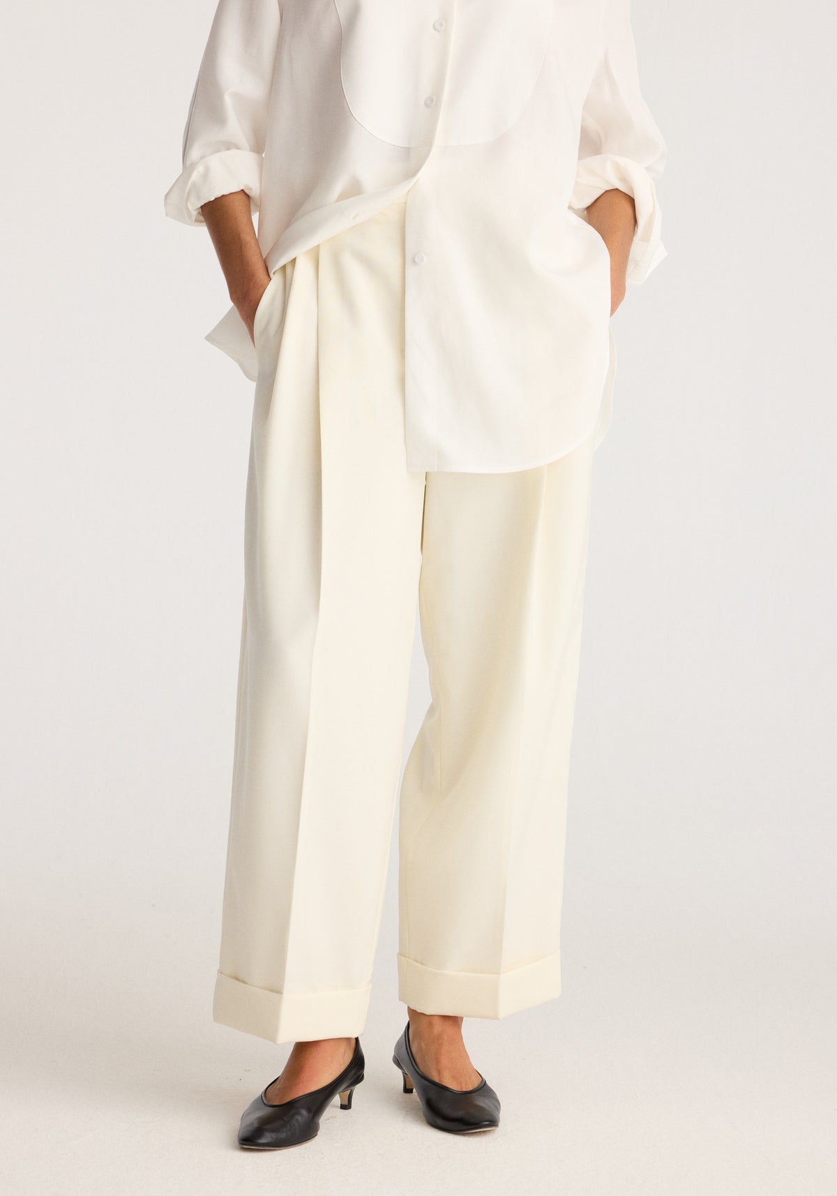 High-waist turn up trousers | off white shown on a model with rolled cuffs, relaxed straight legs, side pockets, and black pointed flats