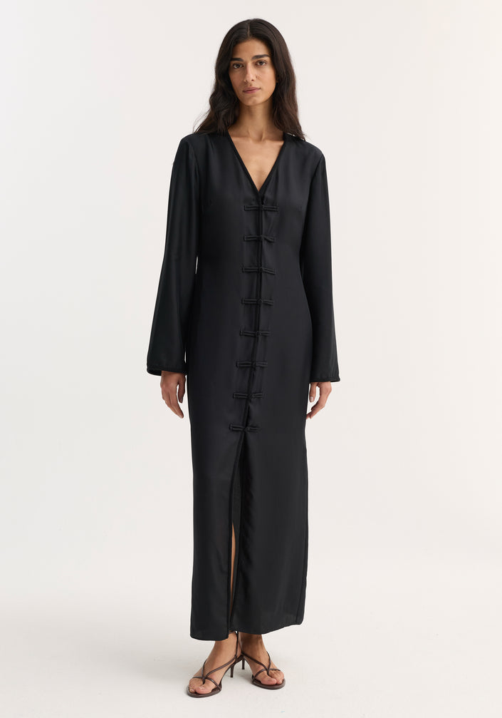 Mandarin silk dress | black: Model in a long, black silk dress with V-neck, pankou closures, long sleeves, and front slit, showcasing elegance and luxurious craftsmanship.