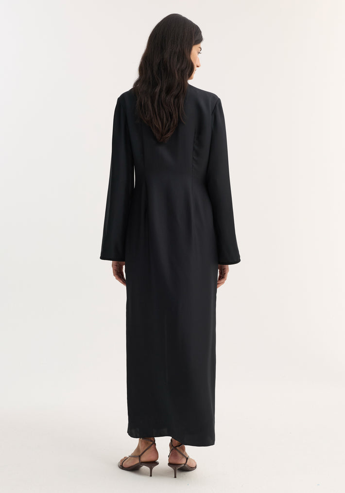 Mandarin silk dress in black, worn by a woman with loose waves, features long sleeves, pankou closures, and a front split, highlighting elegant movement.