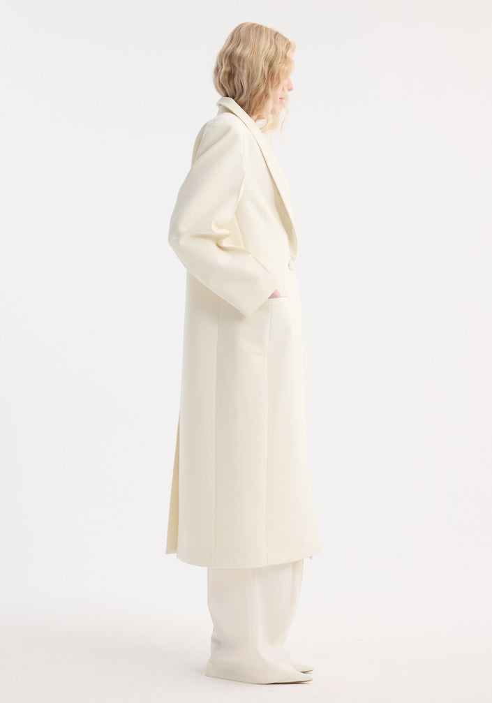 Model in a Signature opera coat | ivory, showcasing a tailored fit with a single-button closure, softly structured shoulders, and a relaxed, minimalist pose.