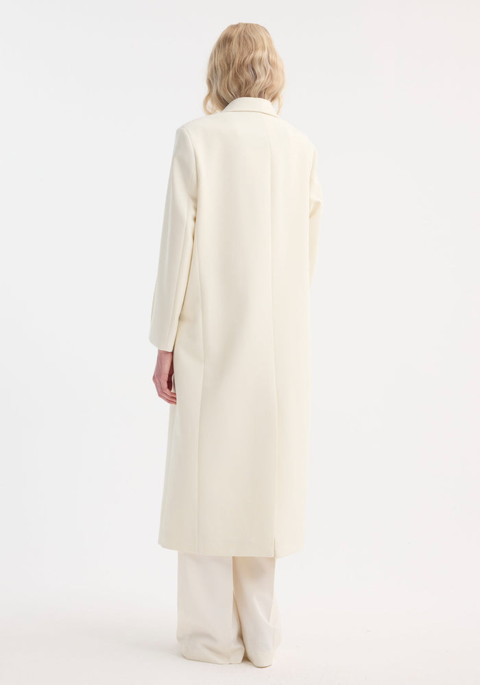 Signature opera coat | ivory drapes elegantly with a double-breasted design, sleek lapels, and a center back slit, offering timeless sophistication.