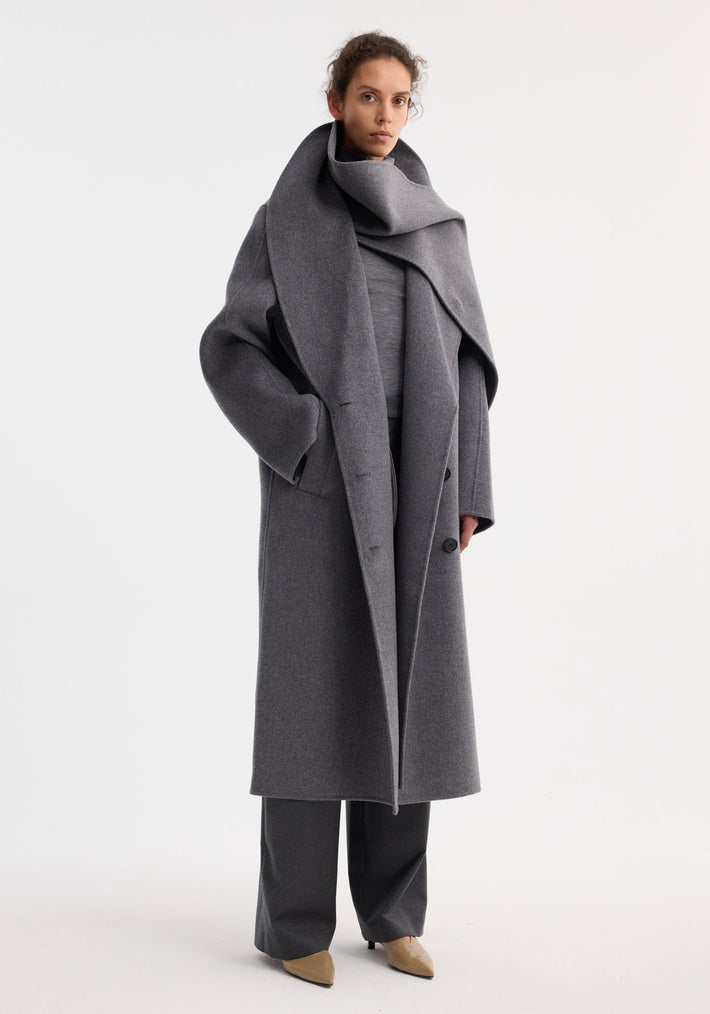 Model wearing a Signature double-faced scarf coat in mid grey melange with a dramatic collar, wide-leg trousers, and beige heels, exuding sophistication.