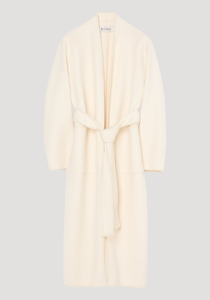 Double-faced kimono style coat in off white, featuring a calf-length wrap design with patch pockets, long sleeves, and a self-tie belt for an adjustable fit.