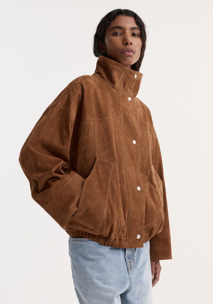 Model in oversized cognac Reinvented Suede Jacket with high stand-up collar, snap-button front, and large patch pockets, paired with light-wash jeans.