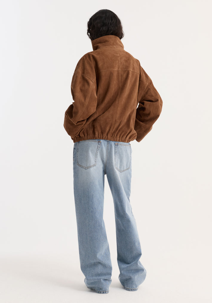 Back view of a person wearing the Reinvented suede jacket in cognac, showcasing its relaxed fit, high collar, and elasticized hem, paired with wide-leg jeans.
