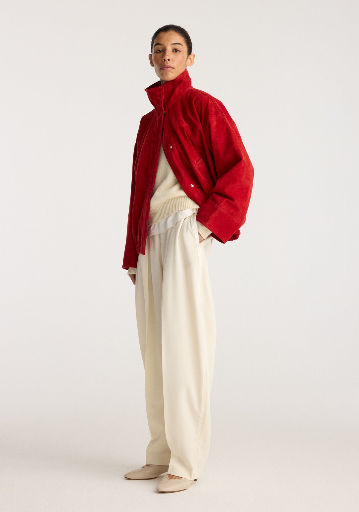 Reinvented suede jacket | red worn by a model with a high collar, button front, and relaxed fit, styled with a cream sweater and wide leg trousers
