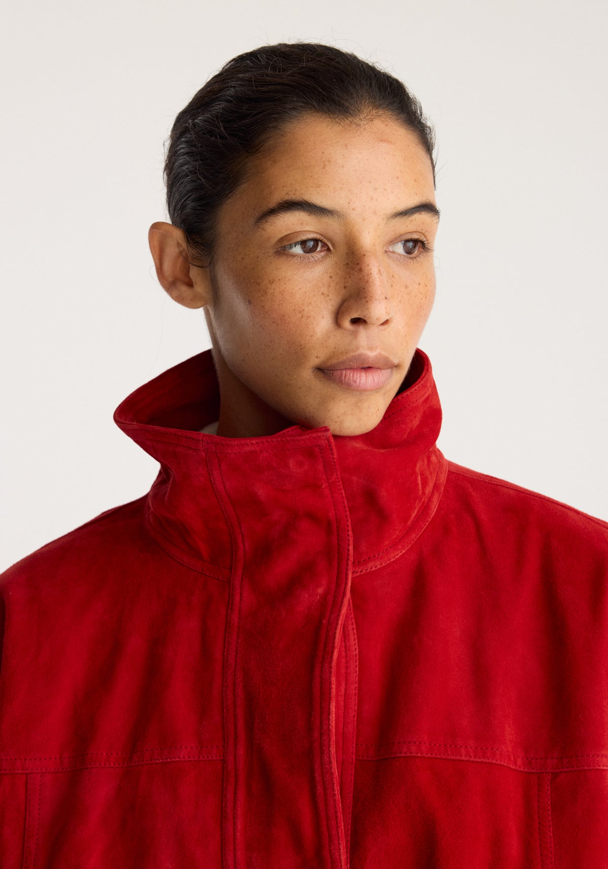 Reinvented suede jacket | red in close up with a model wearing the red suede jacket featuring a high collar and front zip closure