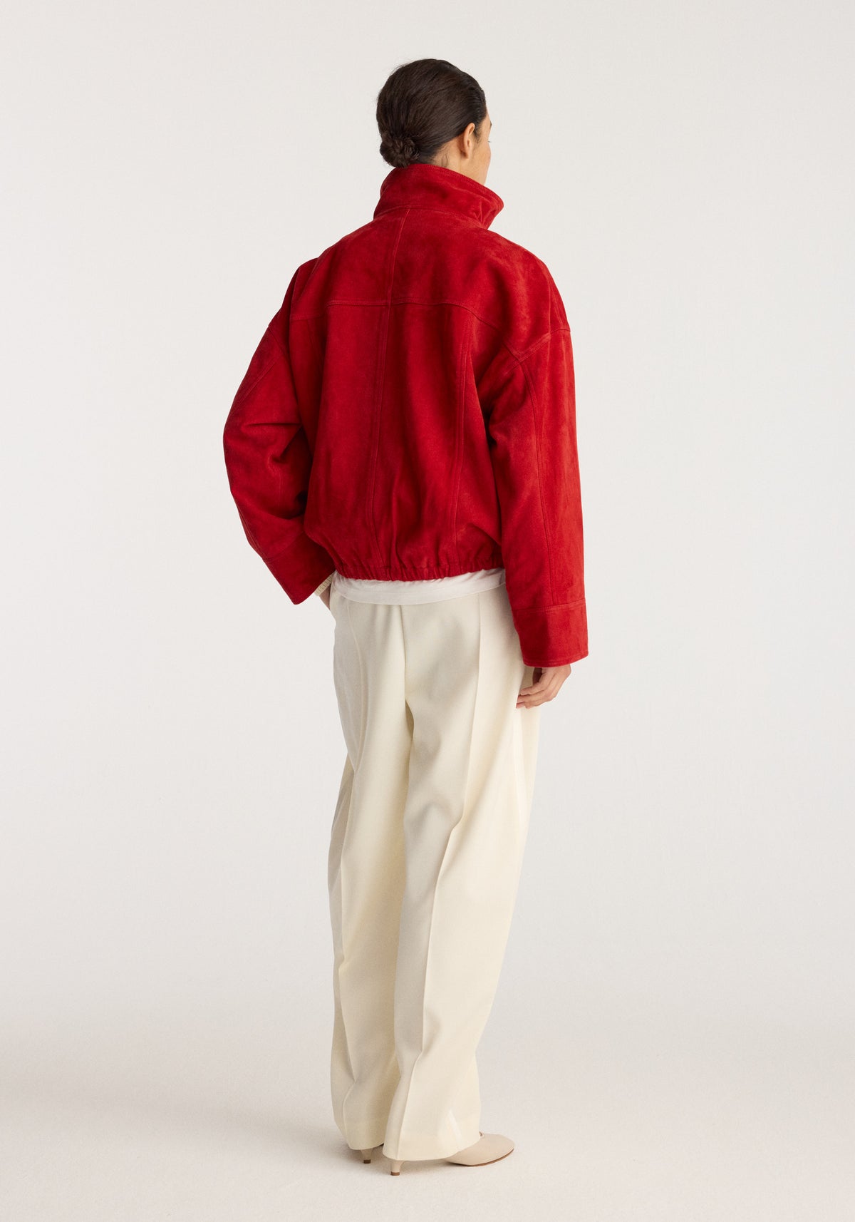 Reinvented suede jacket | red shown from the back on a model with a high collar and long sleeves, styled with cream trousers and neutral shoes