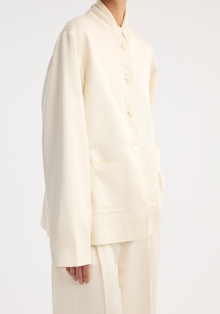 Mandarin pearl button satin jacket in cream, featuring a mandarin collar, pearl buttons, and patch pockets, paired with matching wide-leg trousers.