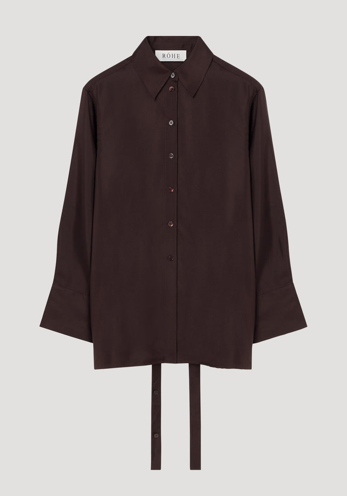 Deconstructed silk shirt in mahogany with an open back, pointed collar, and fabric ties for styling versatility, featuring a RÓHE label inside.