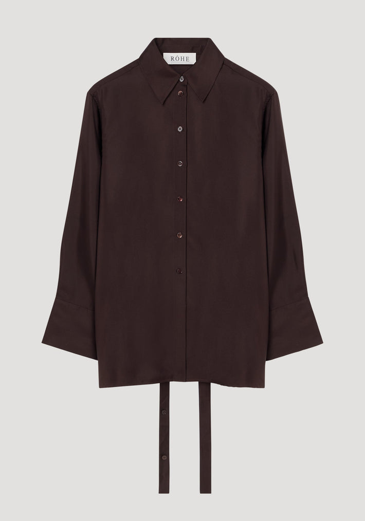 Deconstructed silk shirt in mahogany with an open back, pointed collar, and fabric ties for styling versatility, featuring a RÓHE label inside.