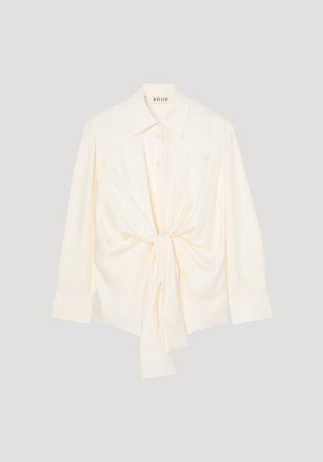 Silk knotted shirt | cream: Cream-colored, long-sleeve blouse with a pointed collar, featuring a unique twisted knot design at the waist for a draped effect.