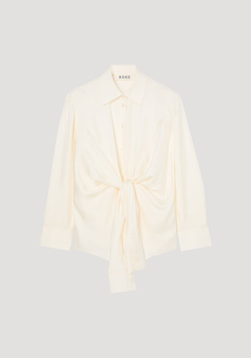 Silk knotted shirt | cream: Cream-colored, long-sleeve blouse with a pointed collar, featuring a unique twisted knot design at the waist for a draped effect.