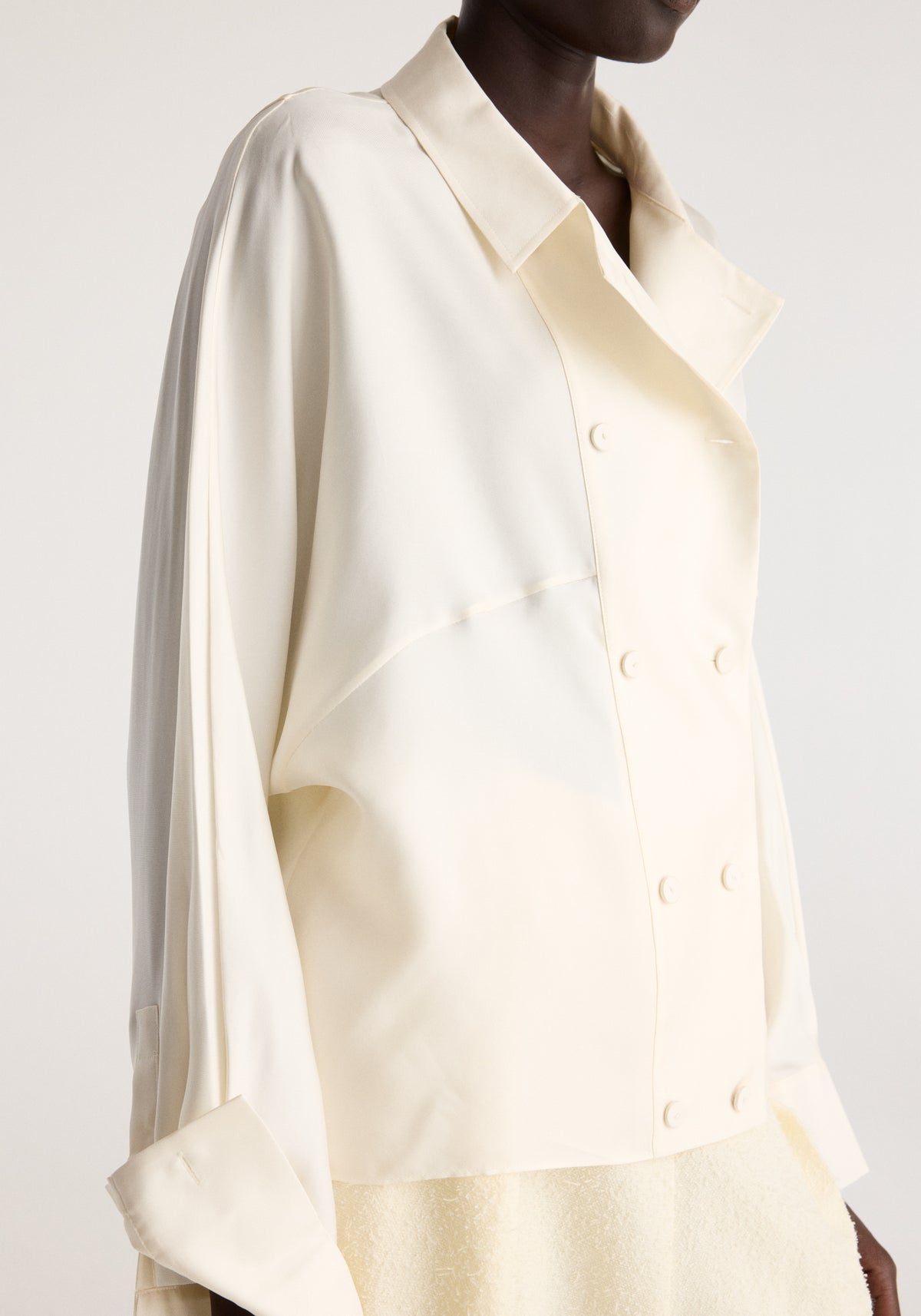 Double breasted silk top | cream shown on a model with a pointed collar long sleeves folded cuffs and double breasted button fastening