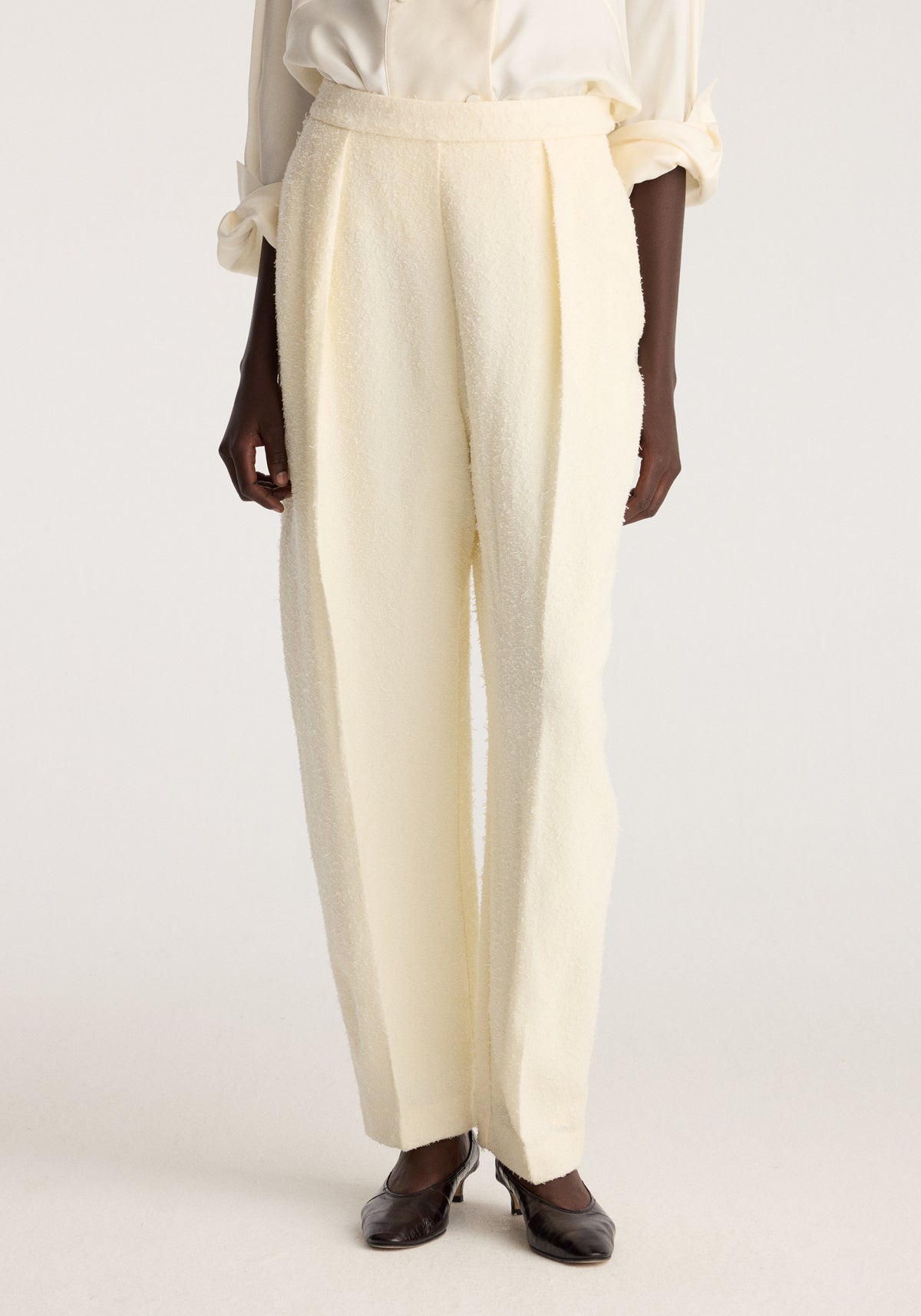 Puck - Sculptural bouclé tailored trousers | cream shown on a model with a high waist and relaxed straight leg styling with a white blouse and black shoes
