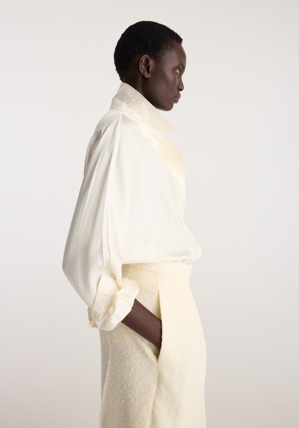 Puck - Sculptural bouclé tailored trousers | cream shown in side profile on a model wearing cream trousers and a draped ivory blouse