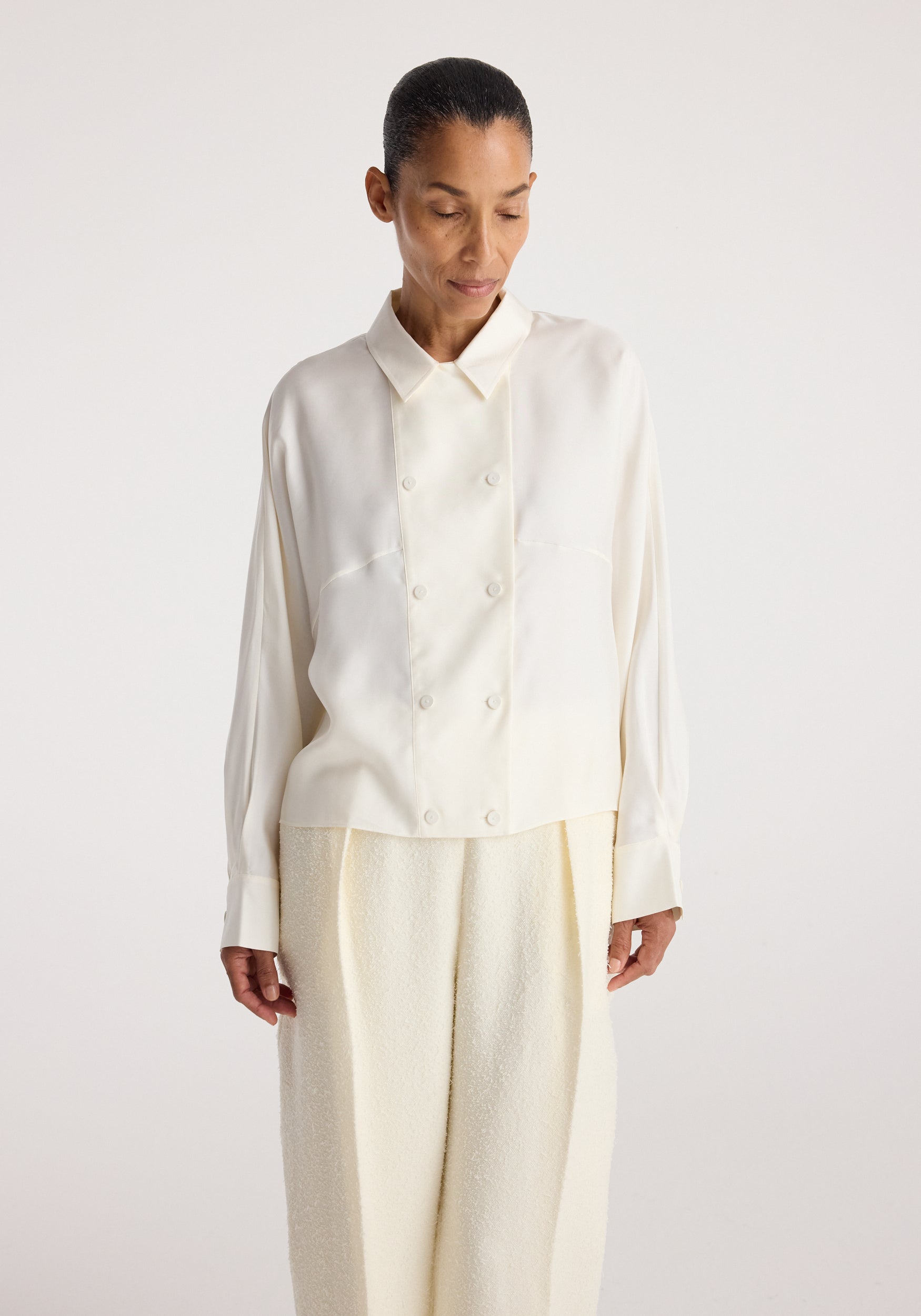 Model wearing the Double breasted silk top | cream, featuring a collared neckline, long sleeves, front buttons, and a relaxed fit.