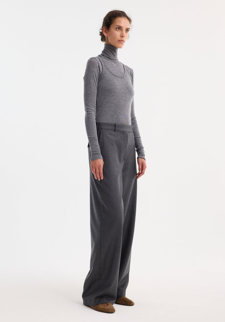 Woman wearing Double-layer wool top in mid grey melange, featuring a fitted turtleneck and tank, paired with wide-leg trousers and brown suede flats.